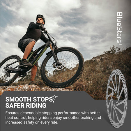 Mountain biker riding on a trail with a 180mm stainless steel disc brake rotor featured in the foreground.